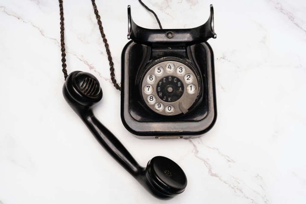 Old-fashioned rotary dial telephone with receiver on white marble background.
